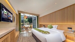 Une chambre d’hôtel moderne avec un grand lit, une tête de lit en bois, un bureau avec une chaise et une grande fenêtre.