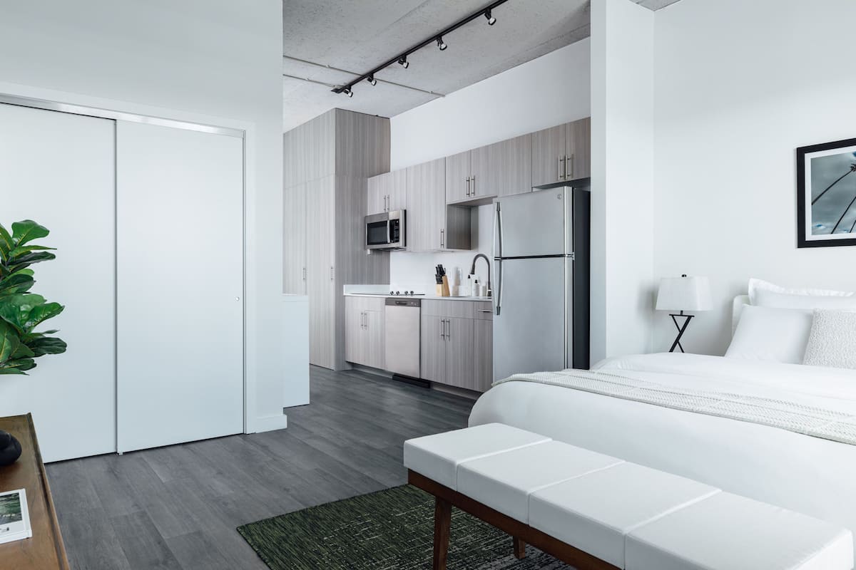 A modern bedroom with a large bed, a bedside table, and a green rug.
