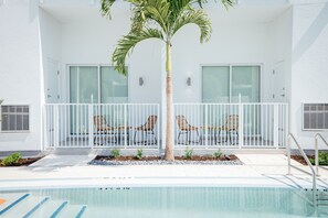 A pool area with a palm tree, white railing, and two lounge chairs. - Mint House St. Petersburg Downtown by Kasa (St. Petersburg)