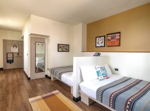 A hotel room with two single beds, a wooden floor, a mirror, a small desk, and a wall-mounted telephone. - Moxy Phoenix Downtown (Phoenix)