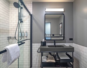 A modern bathroom with a glass shower enclosure, a black sink, and a mirror above it. - Moxy Phoenix Downtown (Phoenix)