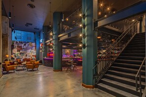 A spacious lobby with a bar area, seating, and a staircase. - Moxy Phoenix Downtown (Phoenix)