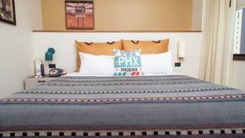 A hotel room with a bed, a nightstand with a lamp, a wall clock, and a framed picture.