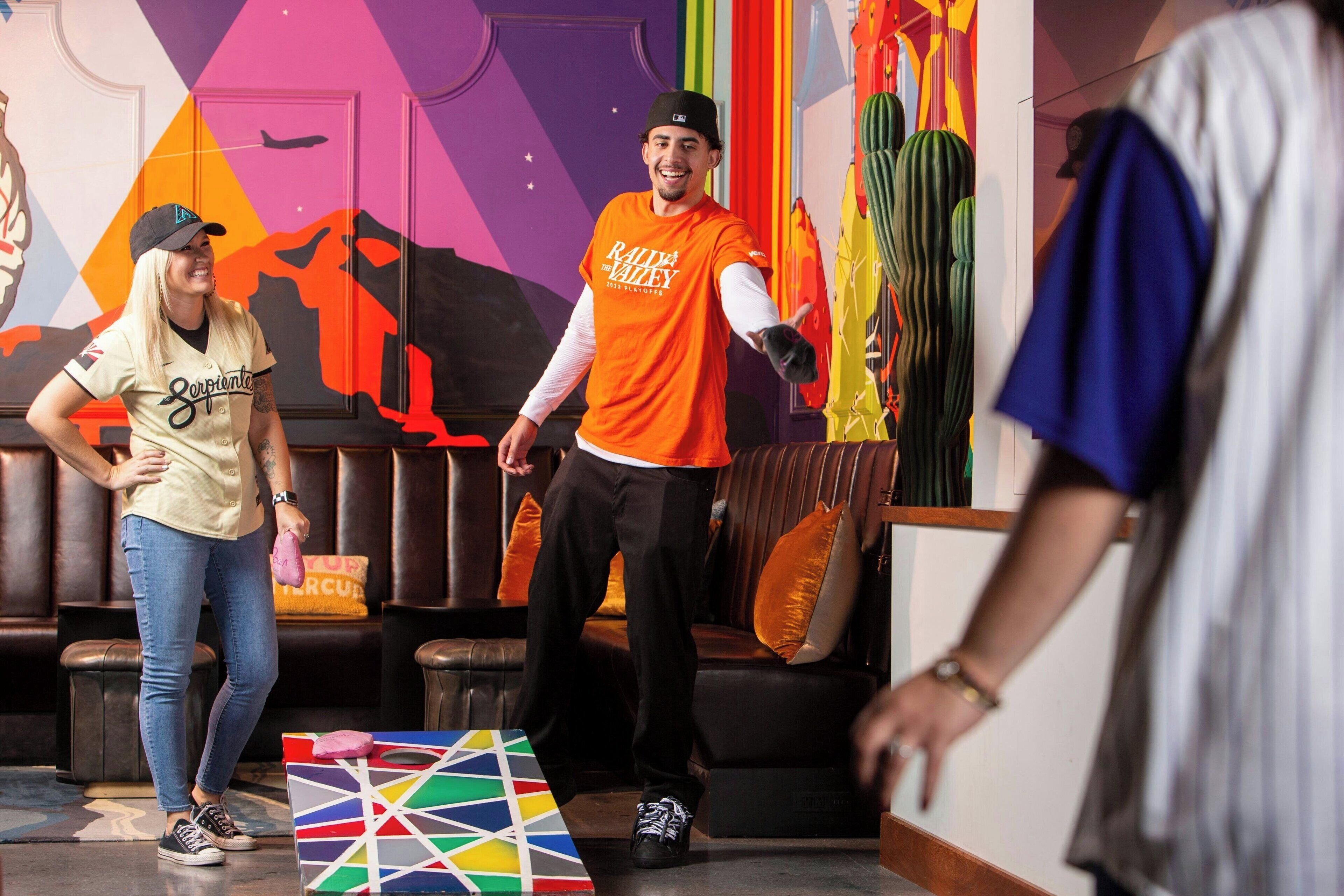 A room with a sofa, a colorful geometric table, and a wall with a mural.
