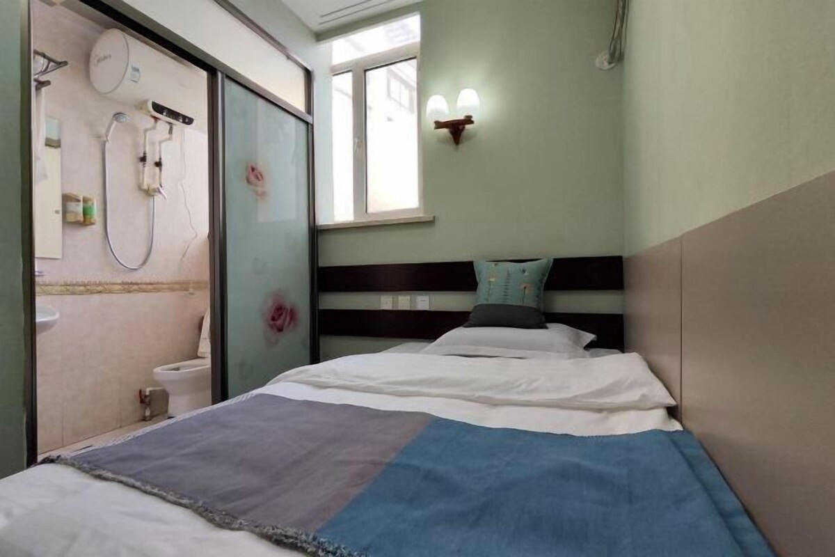Un dormitorio con una cama, una ventana y un baño visible a través de una puerta abierta.