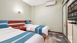 Ett hotellrum med två sängar, en tv, en luftkonditioneringsanläggning och ett klinkergolv.