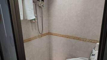 A small, tiled bathroom with a shower, a toilet, and a towel rack.