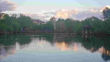 A calm lake with a gazebo and a pavilion in the distance.