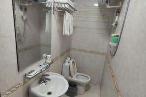 Un baño con lavamanos, inodoro, ducha y espejo.