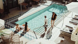 Zona de piscina con sillones reclinables, una mesa junto a la piscina y una terraza con baldosas.