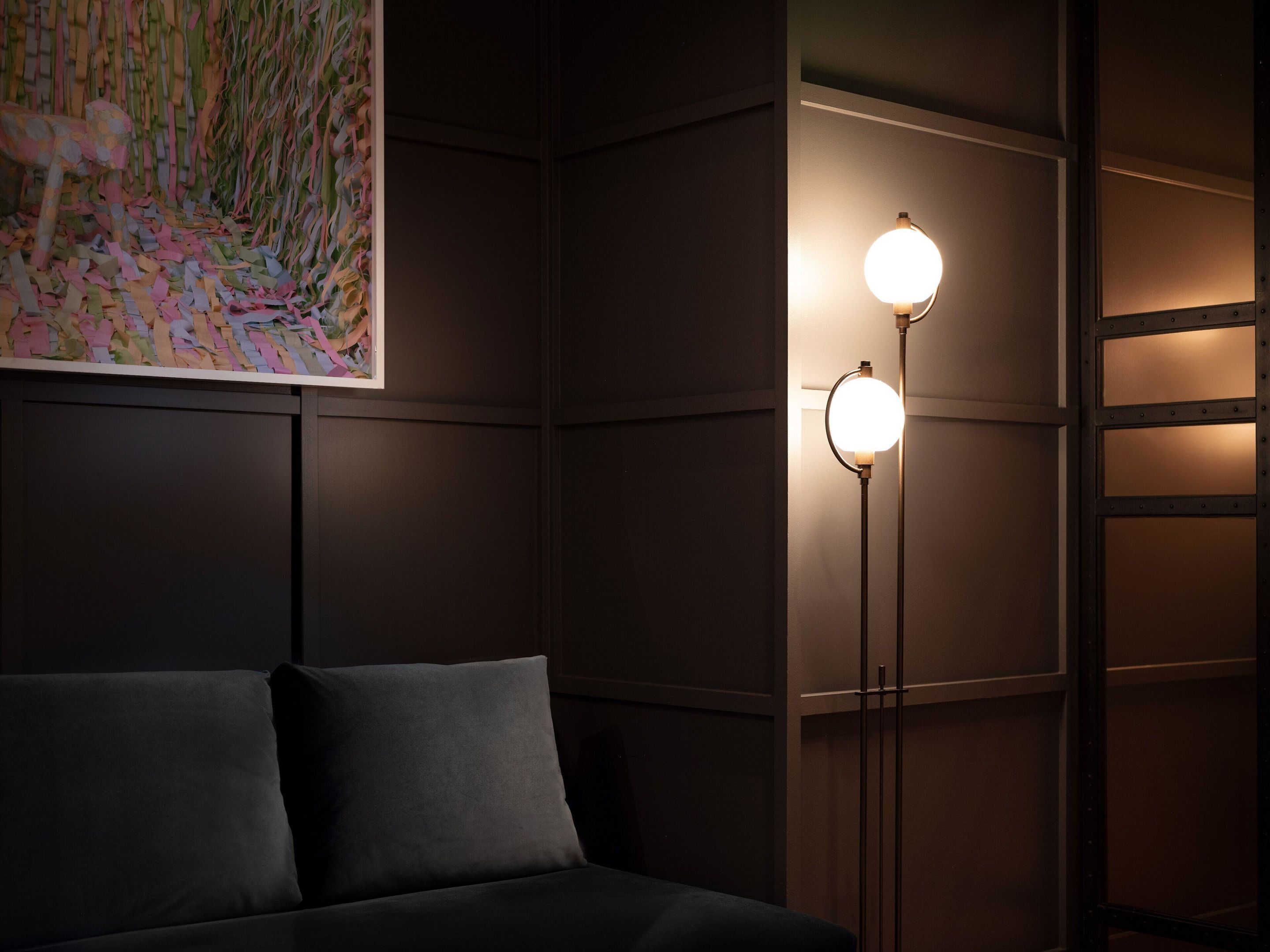 A dark room with a sofa and two floor lamps.
