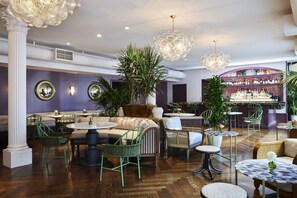 Zona de bar con diferentes opciones de asientos, incluyendo sofás, sillas y mesas redondas.