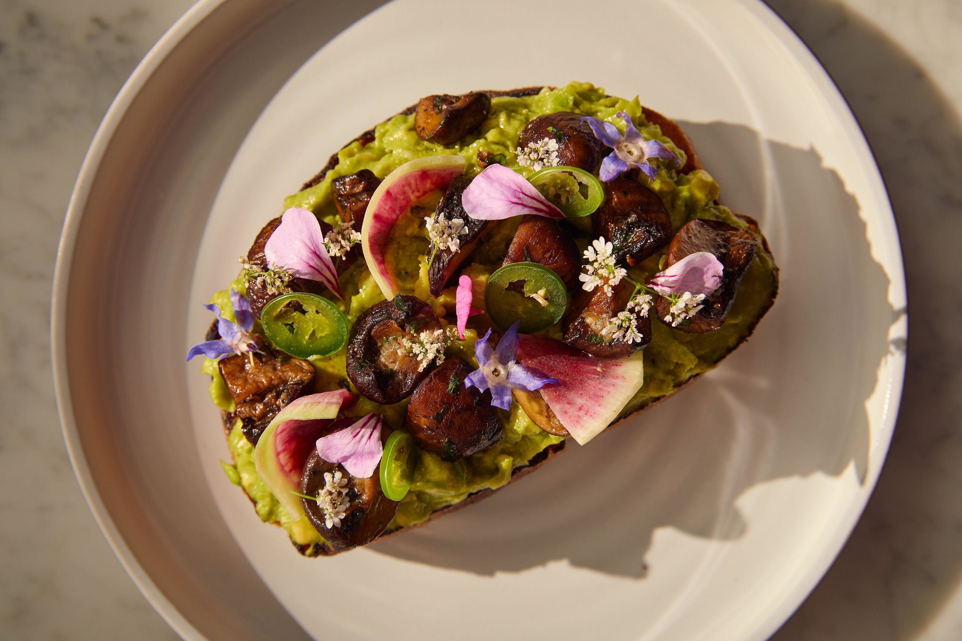 Un plat composé d’avocat, de champignons et agrémenté de fleurs décoratives.