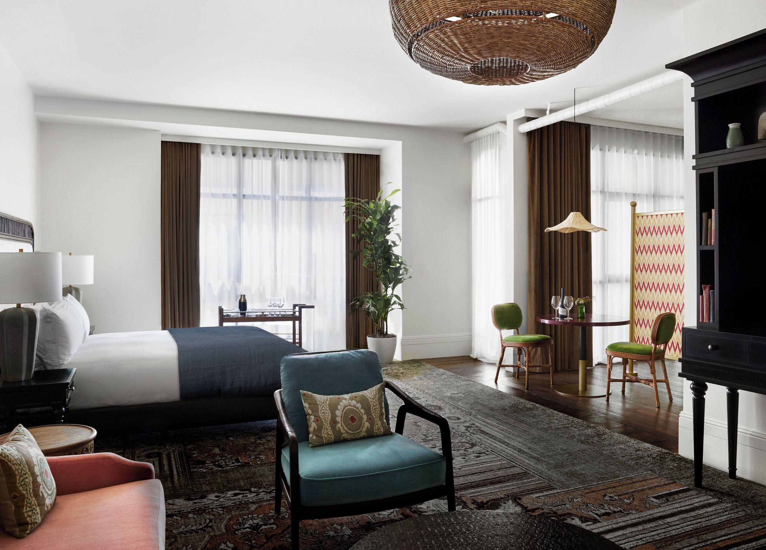 Una habitación de hotel con cama, escritorio, silla, sofá, lámpara y estantería.