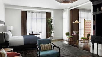 Una habitación de hotel con cama, escritorio, silla, sofá, lámpara y estantería.
