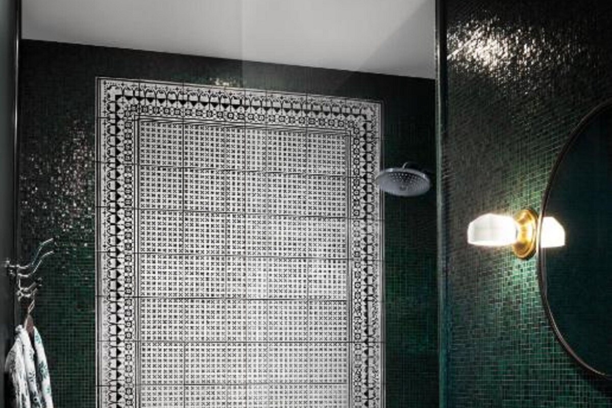 A bathroom with a patterned wall, a shower, and a sink.