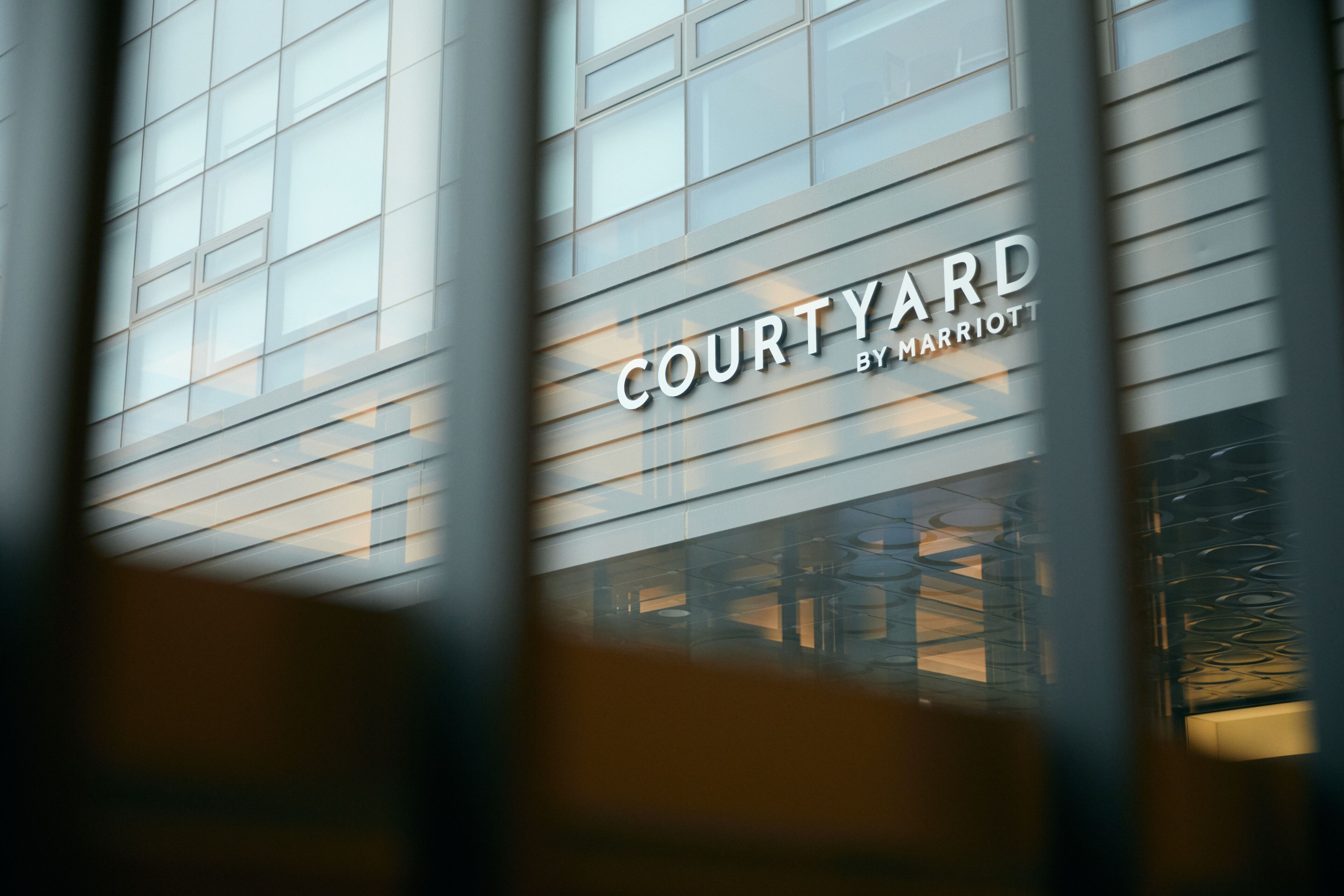 Fachada de un edificio que muestra el texto "COURTYARD BY MARRIOTT", indicando un hotel Marriott.