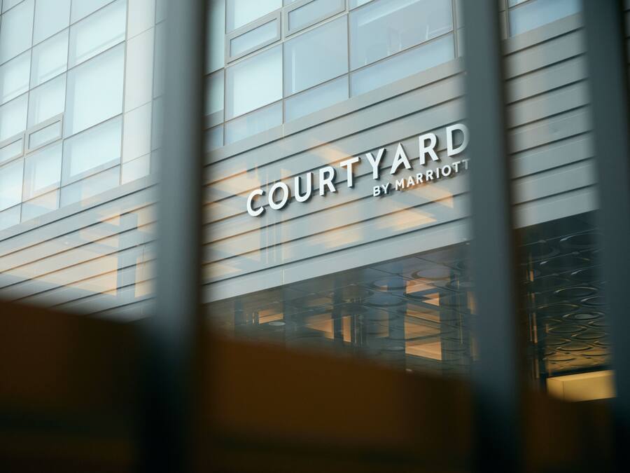 Fachada de un edificio que muestra el texto "COURTYARD BY MARRIOTT", indicando un hotel Marriott.