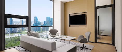 A modern living room with a sofa, chairs, a TV, and a city view.