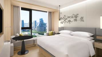 Habitación de hotel moderna con una cama grande, una mesita y vistas a la ciudad.