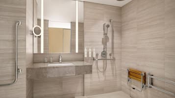 A modern bathroom with a granite sink, a handheld showerhead, and a wooden bath bench.