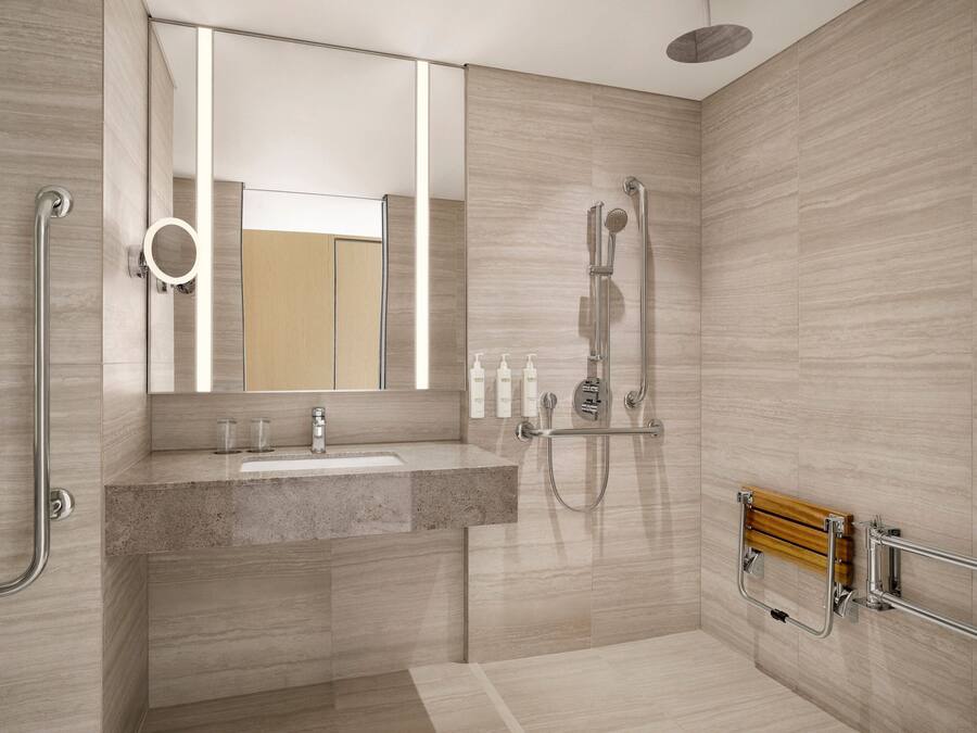 A modern bathroom with a granite sink, a handheld showerhead, and a wooden bath bench.