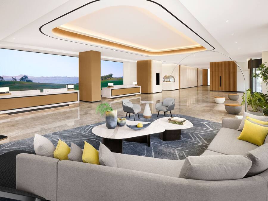 A spacious lobby with a reception desk, seating area, and large windows offering a view of the outdoors.