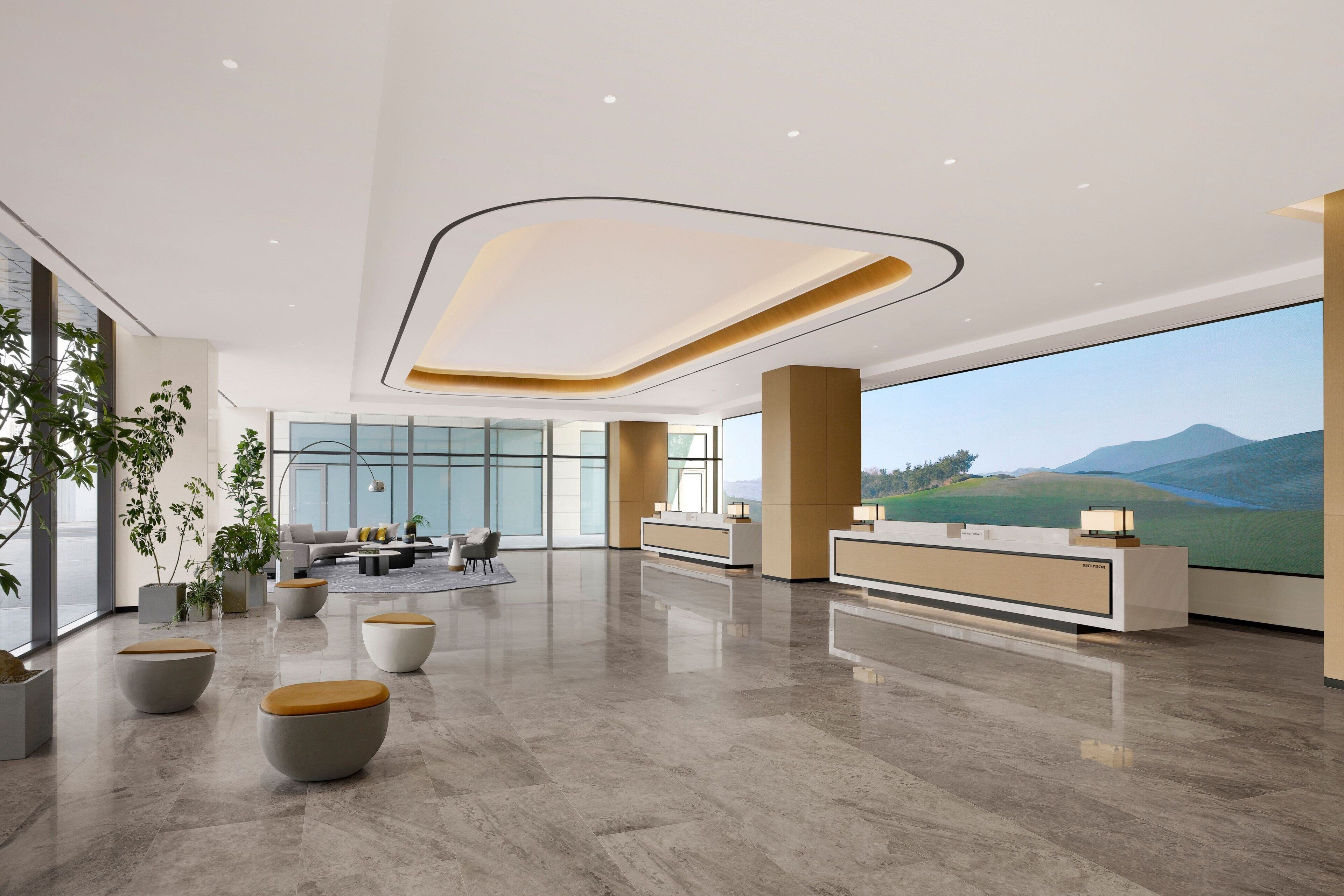 Un vestíbulo espacioso con mostrador de recepción, zona de estar y grandes ventanales con vistas al exterior.