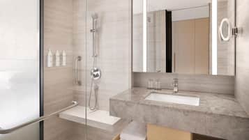 A modern bathroom with a glass shower enclosure, a marble sink, and a large mirror.