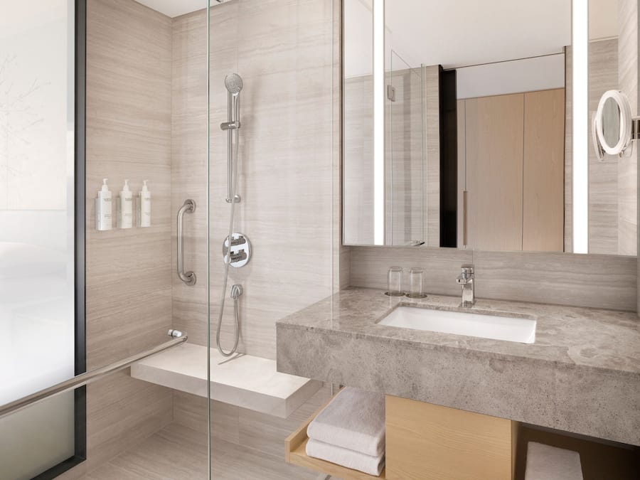 A modern bathroom with a glass shower enclosure, a marble sink, and a large mirror.