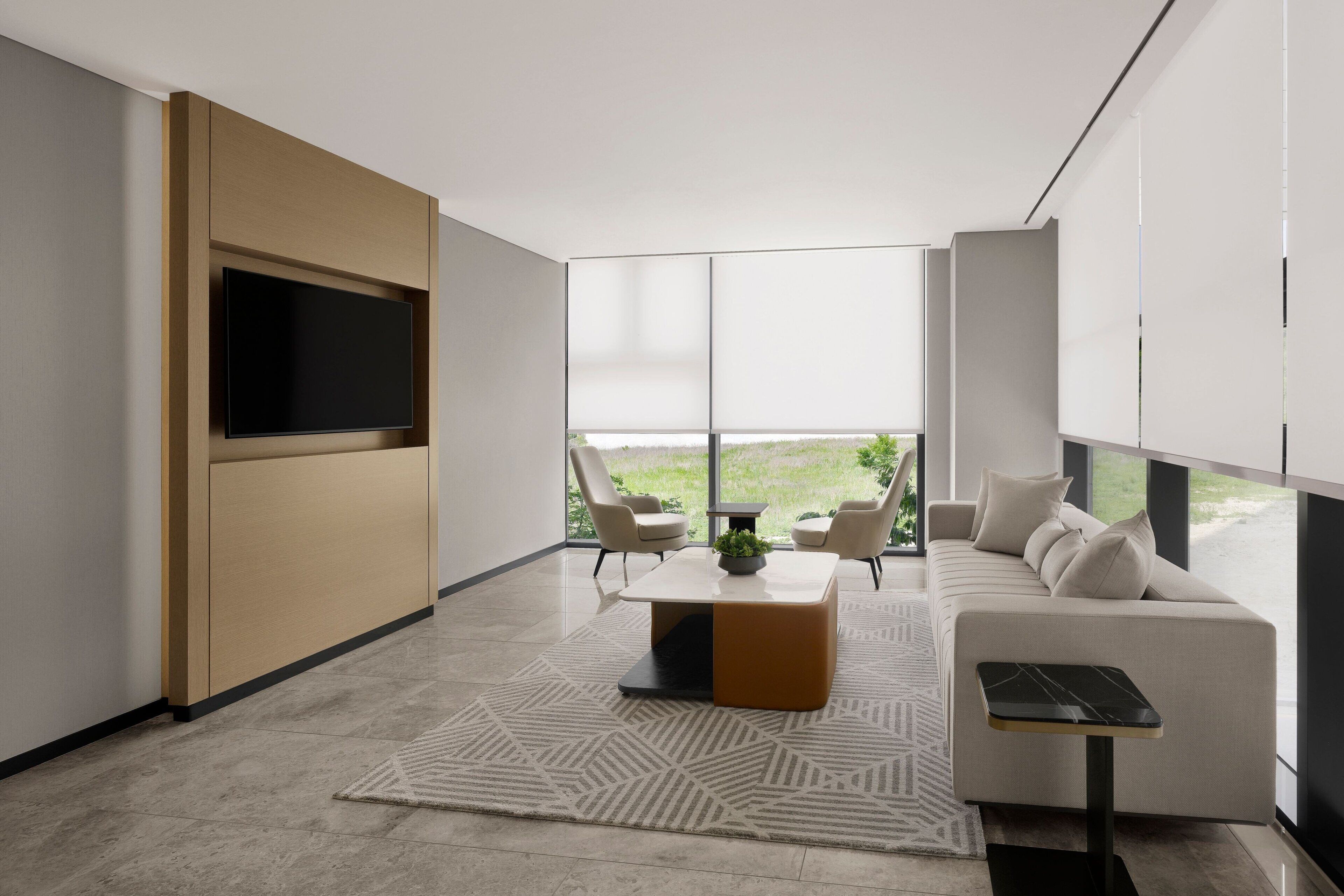 Una sala de estar moderna con un televisor de pantalla plana montado en la pared, un sofá, una mesa de centro y una mesita auxiliar.