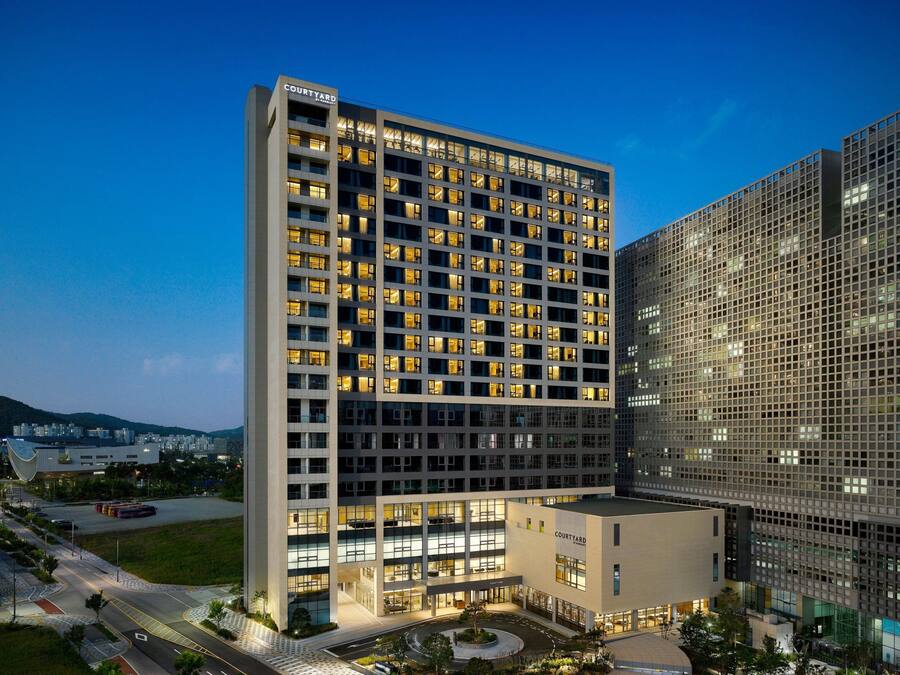 A modern hotel with multiple floors, a courtyard, and a parking area.