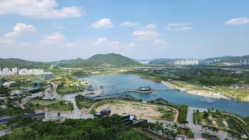 Vista panorámica de una ciudad costera con un río, un puente y un parque con áreas de juegos.