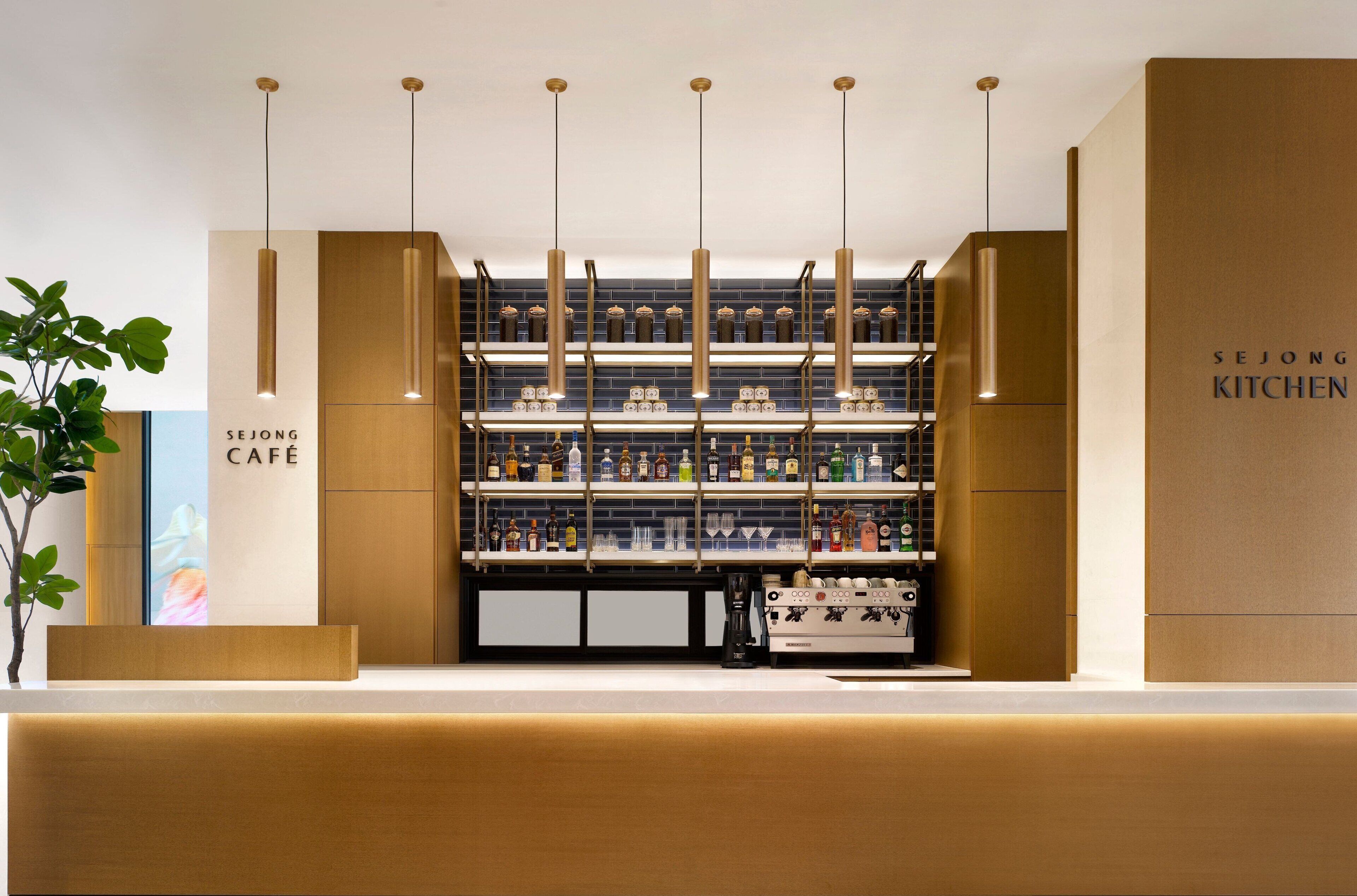 A modern bar area with a Sejong Cafe sign, shelves of liquor bottles, and a coffee machine.
