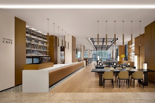 Un interior moderno con una mesa de recepción, zona de estar y estanterías con objetos.