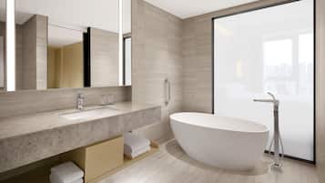 Un baño moderno con una bañera independiente, un espejo grande y una ducha con cabezal de ducha manual.