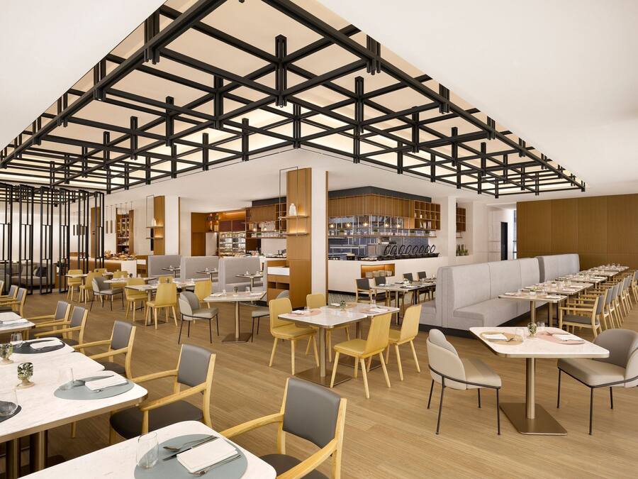 A modern restaurant with a high ceiling, wooden flooring, and a variety of seating options including tables and booths.