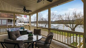 A covered outdoor deck with a table and chairs, overlooking a body of water and a dock. - Tranquil waterfront getaway (Ashland City)