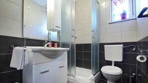 A modern bathroom with a white sink, toilet, and shower. - Apartment Vedrana - great value near beach and free parking (Dubrovnik)