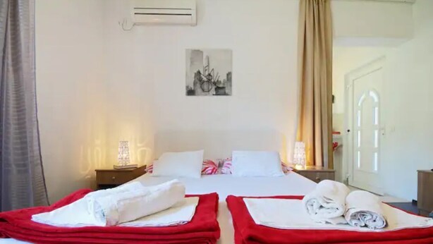 A hotel room with two beds, each with red and white bedding, and a painting on the wall. - Apartment Vedrana - great value near beach and free parking (Dubrovnik)