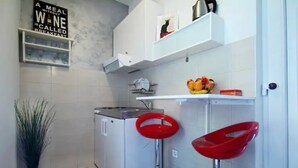 A compact kitchen with white cabinets, a built-in oven, and a fruit bowl on the countertop. - Apartment Vedrana - great value near beach and free parking (Dubrovnik)