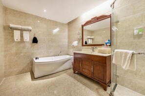 A modern bathroom with a freestanding bathtub, a vanity with a mirror, and a glass shower enclosure. - Sheng Shi Jin Hai Grand Hotel (Nayong)