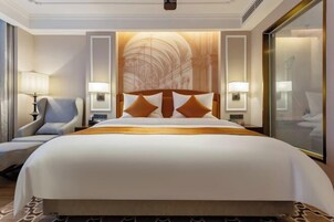 Habitación de hotel con una cama grande, dos lámparas de noche, una silla y un ventanal amplio.