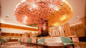 A modern hotel lobby with a circular seating area, a large floral installation on the ceiling, and a reception desk. - Sheng Shi Jin Hai Grand Hotel (Nayong)
