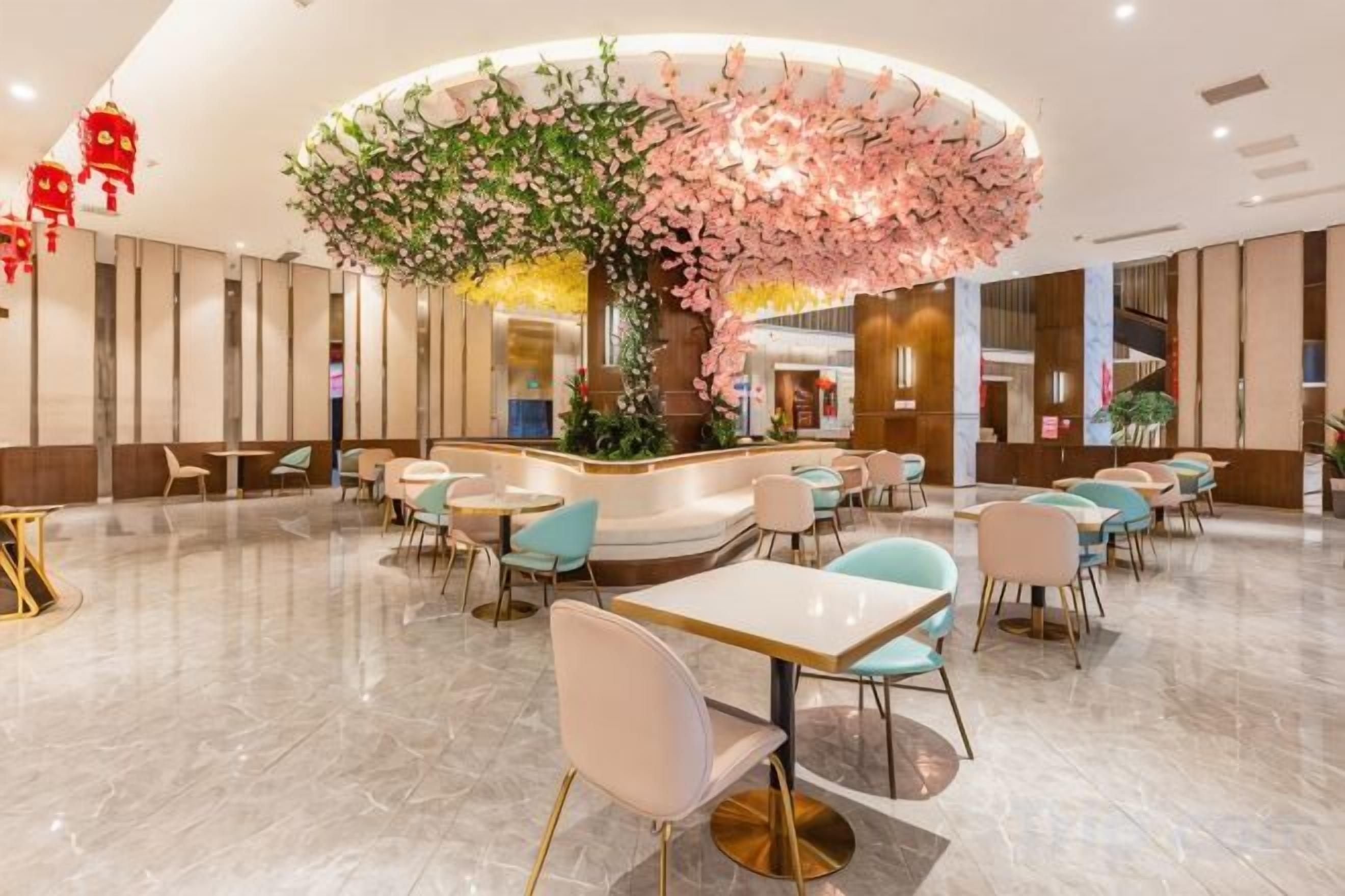 A hotel lobby with a central seating area, a reception desk, and a large decorative tree.