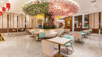 A hotel lobby with a central seating area, a reception desk, and a large decorative tree.