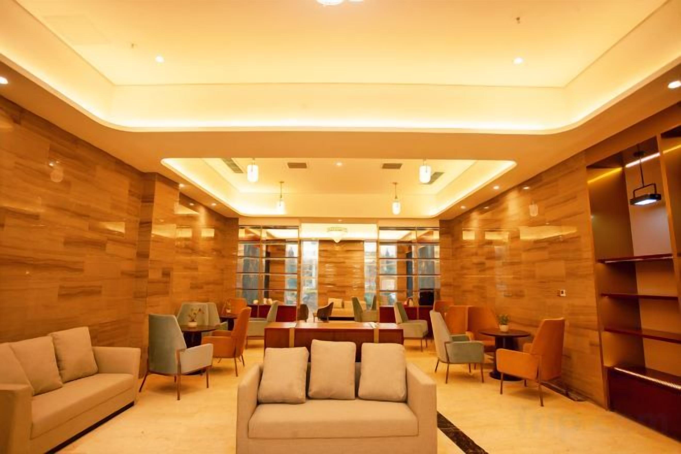 A modern hotel lobby with a sofa, chairs, and a dining area.