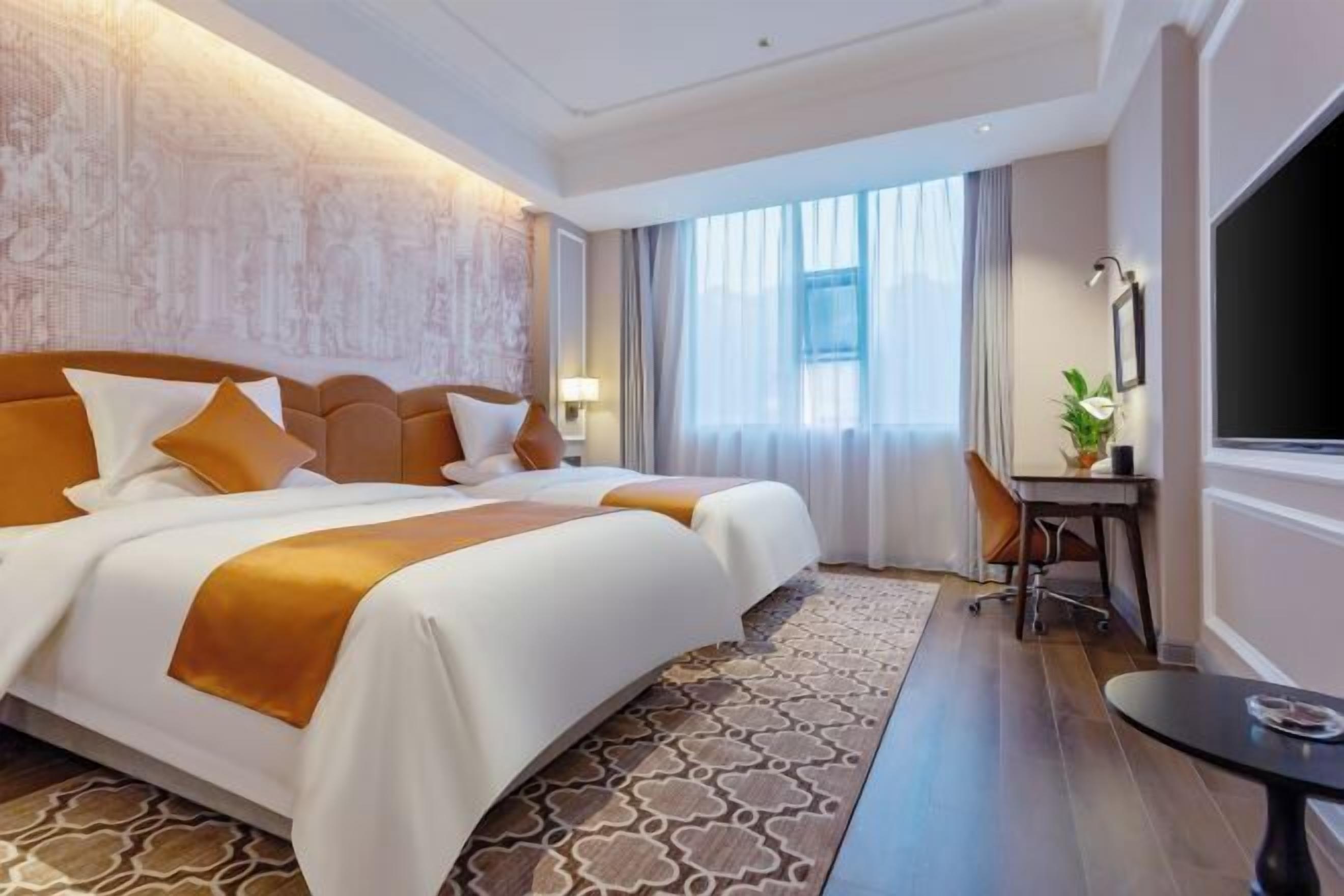 A hotel room with a large bed, a desk, and a TV.