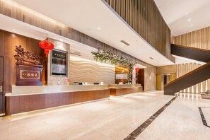 A modern hotel lobby with a reception desk, a staircase, and a decorative wall. - Sheng Shi Jin Hai Grand Hotel (Nayong)