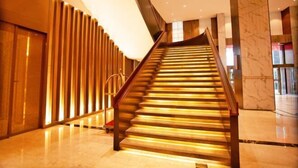 A modern staircase with wooden steps and a metal railing, leading to a higher floor. - Sheng Shi Jin Hai Grand Hotel (Nayong)